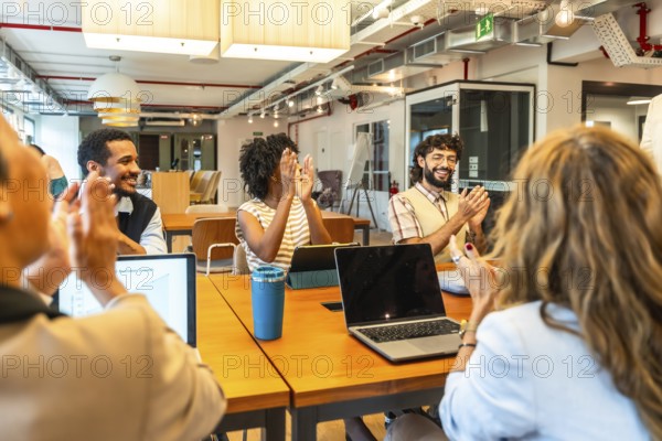 Diverse business colleagues celebrating success and achievement during a corporate meeting, showing appreciation while collaborating and networking in a modern coworking office environment