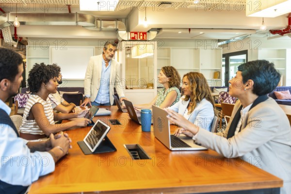 Diverse business professionals conducting a collaborative meeting in a contemporary open plan office setting, actively discussing ideas and working together