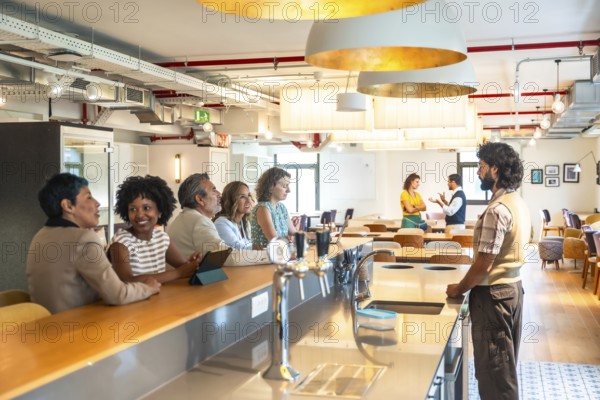Diverse business colleagues enjoying a casual conversation at the counter of a modern coworking office space, fostering team collaboration and a positive work environment during a break