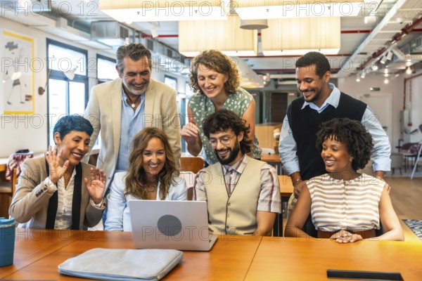 Diverse business colleagues collaborating and smiling during a video call on a laptop in a modern coworking office, fostering teamwork and remote communication