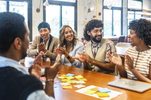 Coworkers clapping and smiling during a collaborative office meeting, showcasing teamwork, appreciation, and positive engagement in a modern coworking space