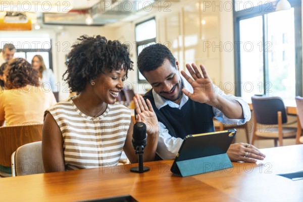 Diverse colleagues creating digital content together, streaming a live video podcast from their modern coworking office space, engaging with their audience and collaborating online