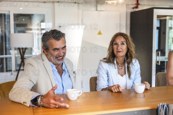 Diverse business colleagues engaging in a discussion and creative conversation during an informal meeting in a modern coworking office space, sharing ideas and expertise