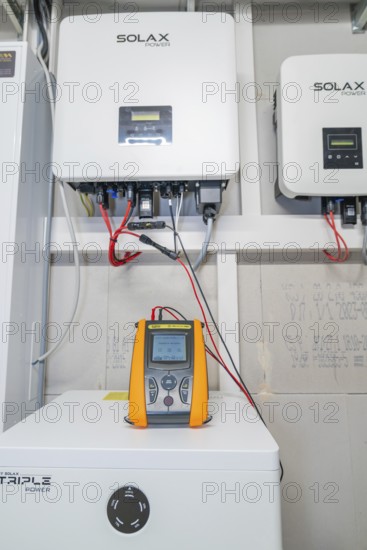 PVCheck PRO in front of installed Solax devices with red cable connections