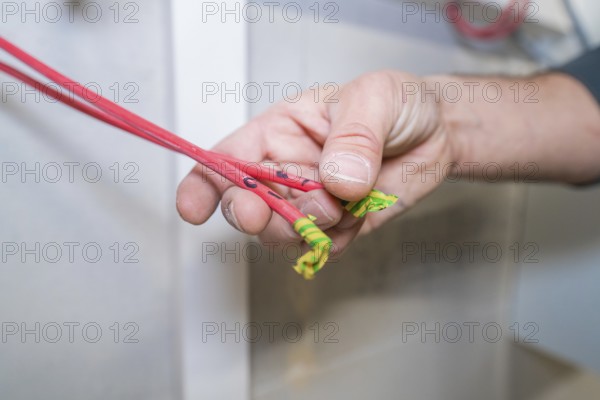 Close-up of a hand holding red and green-marked cables