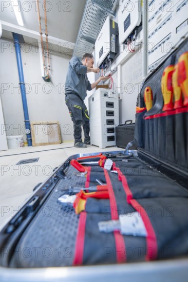 Electrician working in a technical room with toolbox in the foreground