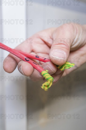 Hand holds red and green marked cable ends close to the camera