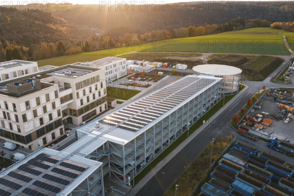 Industrial complex with solar systems next to green fields in the evening light, new hospital, Calw health campus, Black Forest, Germany