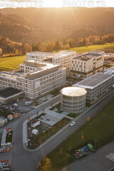 Modern buildings in rural landscape with forests and fields at sunset, aerial view, new hospital, Calw health campus, Black Forest, Germany