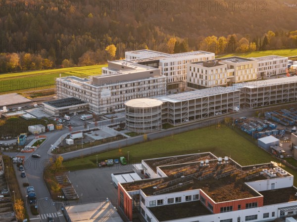 Building complex surrounded by autumn landscape and industrial area, aerial view at sunset, new hospital, Calw health campus, Black Forest, Germany