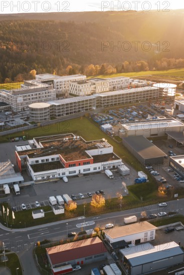 Aerial view of a building complex and industrial areas in autumn surroundings at sunset, new hospital, Calw Health Campus, Black Forest, Germany