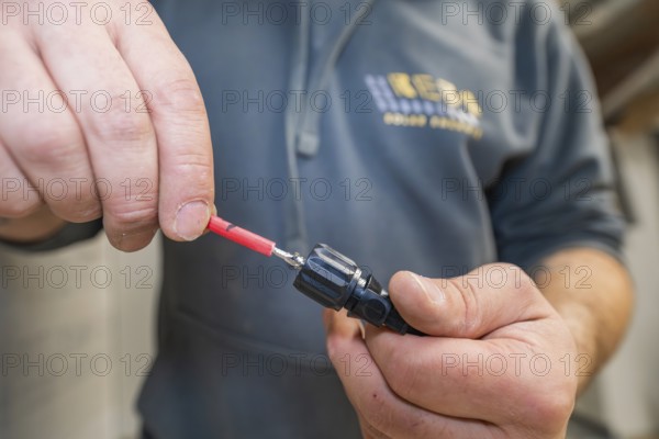 Connecting a cable to a plug from an electrician, hands in close-up