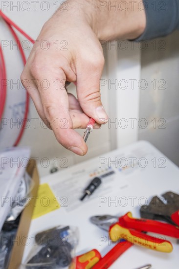 Electrician holds a plug, tools and packaging in the background