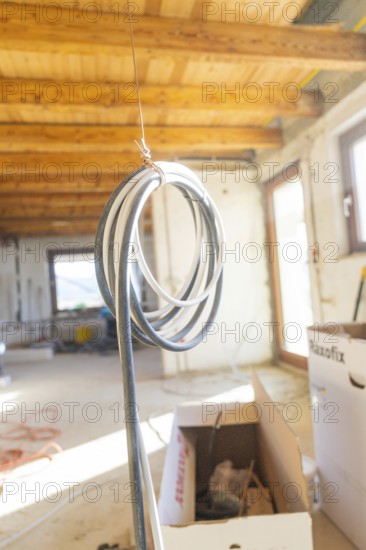 A long cable hangs under a wooden ceiling on a construction site