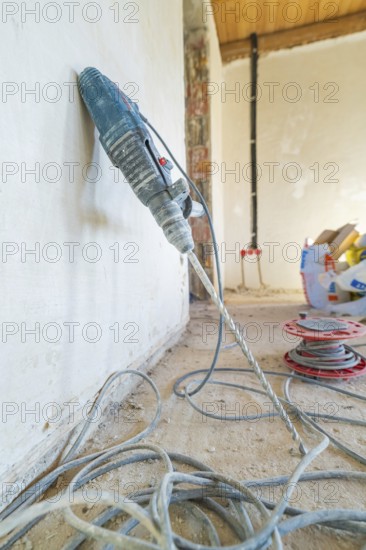 A drill is leaning against a dusty wall on a construction site