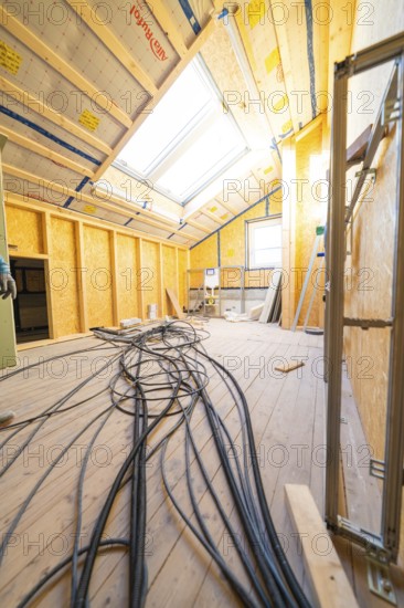 Conversion in an attic with visible wiring and incoming daylight through skylights