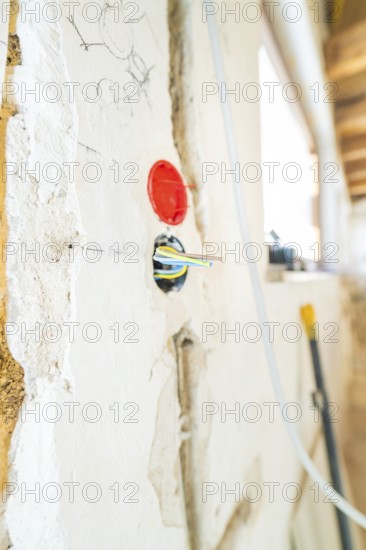 Cable and socket stick out of an unfinished wall with sketches during renovation