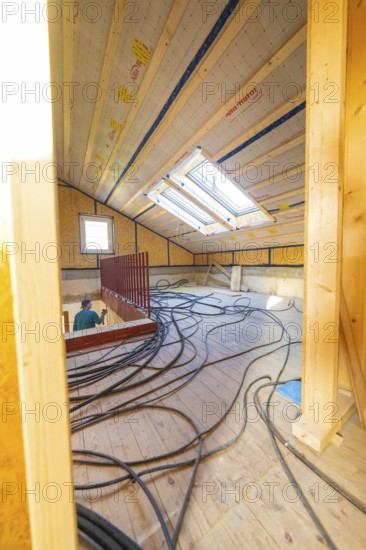 An attic under construction with wood paneling and cables