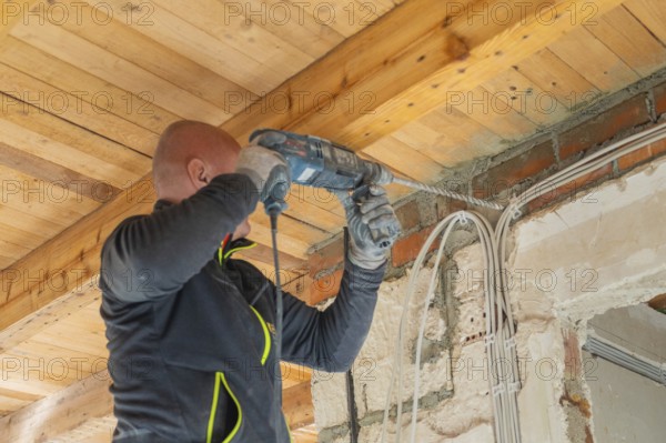 Person operates hammer drills on the ceiling in a building during renovation work
