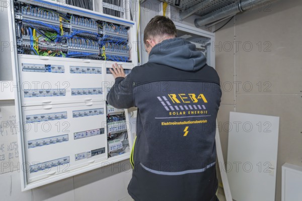 Electrician works in a control cabinet in a technical room