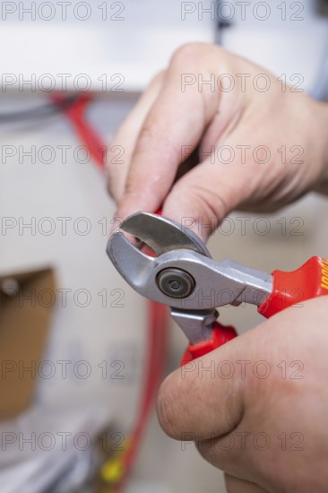 A person uses a red side cutter