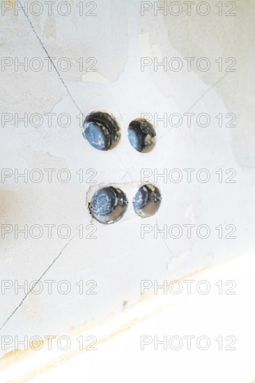 Four drill holes in a plastered wall, prepared for electrical installation