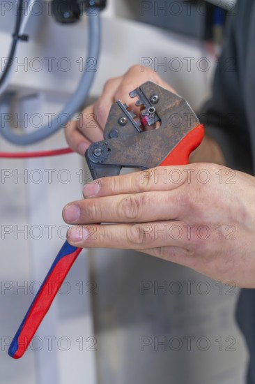 Electrician processes cables with pliers, workshop environment