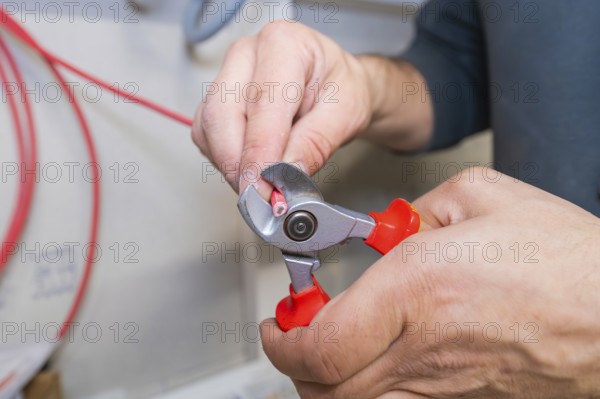 Close-up of a hand cutting a cable with pliers