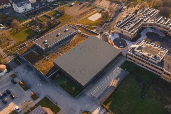 Aerial view of a modern building complex with green spaces and sun in the background, Althengstett sports center and swimming pool, Calw district, Germany