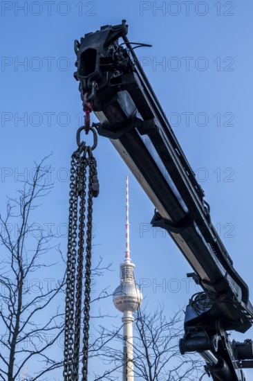 Crane boom with steel chains obscures view of the TV tower on Alexanderplatz, Berlin, Germany
