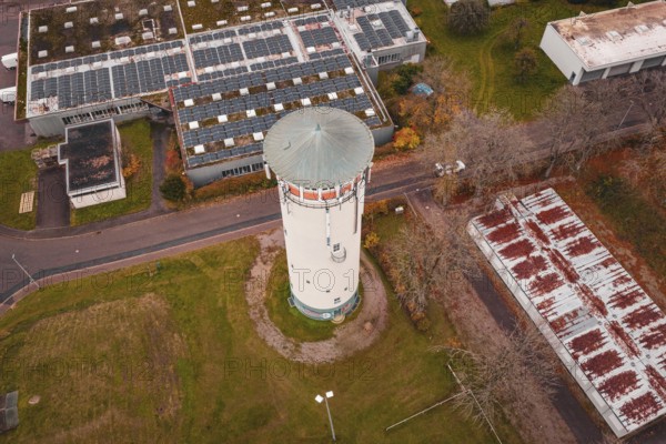 Aerial view of a water tower and surrounding buildings with rusty roofs and solar panels, water tower, Pfalzgrafenweiler, Freudenstadt district, Germany