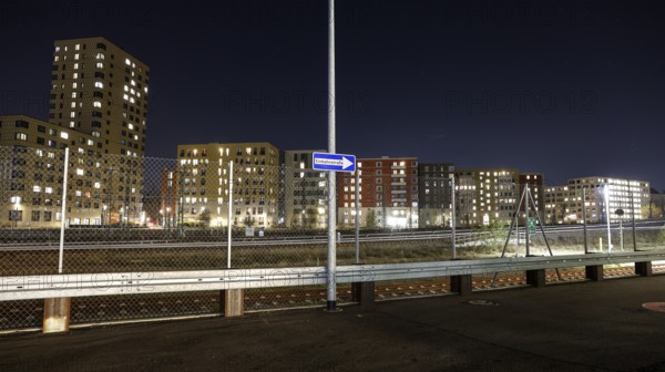 One way street on the fence, behind it a passing ICE train, illuminated apartments in a new housing development, Berlin, 23.11.2025, Berlin, Berlin, Germany