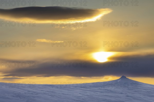 Midnight sun over snow covered mountain in Arctic landscape at Mohnbukta, bay at western shore of Storfjorden in Sabine Land, Spitsbergen, Svalbard