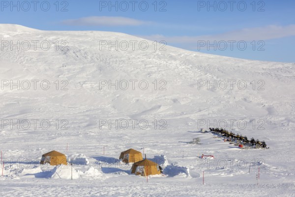 Snowmobiles, snow scooters at Arctic expedition camp with tents protected by tripwire fence against polar bears at Mohnbukta, Spitsbergen, Svalbard