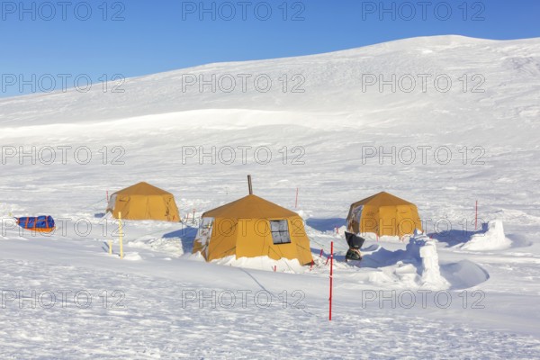 Arctic expedition camp with tents in the snow, protected by tripwire polar bear alarm fence at Mohnbukta, Spitsbergen, Svalbard, Norway