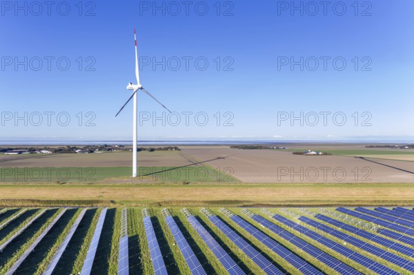 Aerial view over hybrid power plant combing solar photovoltaic modules and wind turbines, North Frisia, Schleswig-Holstein, Germany