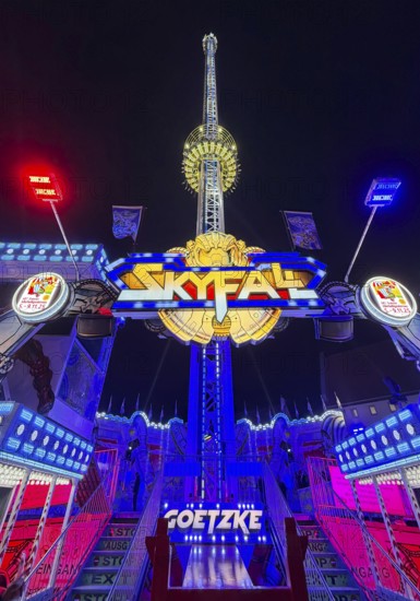 Colourfully illuminated Skyfal free fall tower at night at the All Saints Fair, Soest, North Rhine-Westphalia, Germany