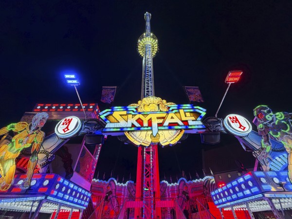 Colourfully illuminated Skyfal free fall tower at night at the All Saints Fair, Soest, North Rhine-Westphalia, Germany