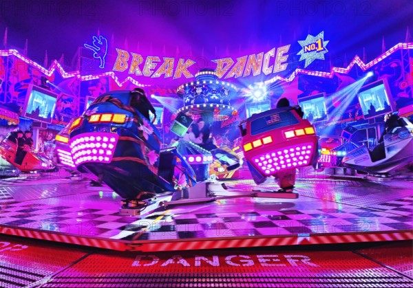 People in the colorful illuminated break dance ride at night at the All Saints Fair, Soest, North Rhine-Westphalia, Germany