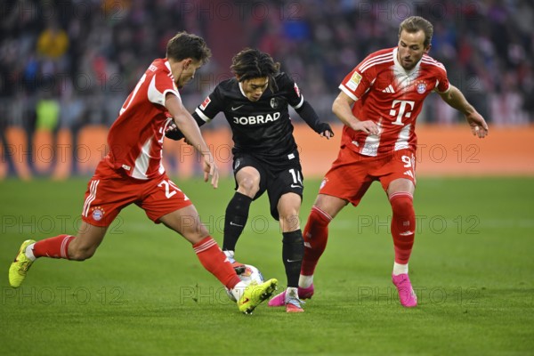 Duel, action Yuito Suzuki SC Freiburg SCF (14) against Tom Bischof FC Bayern Munich FCB (20) (left) Harry Kane FC Bayern Munich FCB (09) Allianz Arena, Munich, Bayern, Germany