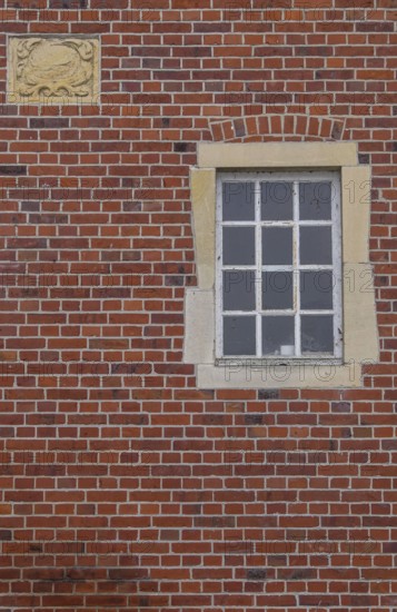 A rectangular window and a coat of arms in a red brick façade, Düstermühle, Münsterland, North Rhine-Westphalia, Germany