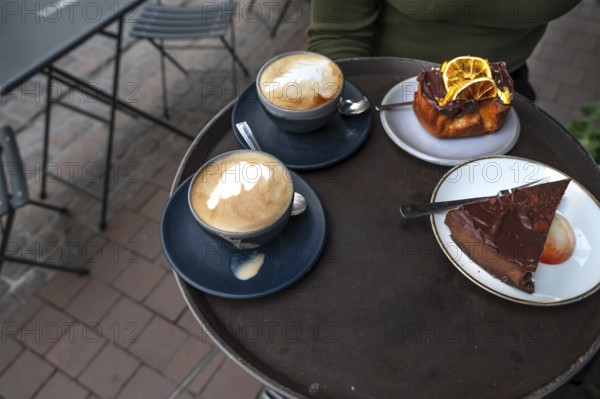 Cappuccino and cake served on a tray in a street café, Hanseatic City of Lübeck, Schleswig-Holstein, Germany