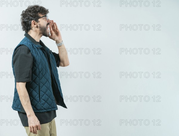 Casual young man in glasses shouting a promotion. Male person shouting an announcement isolated