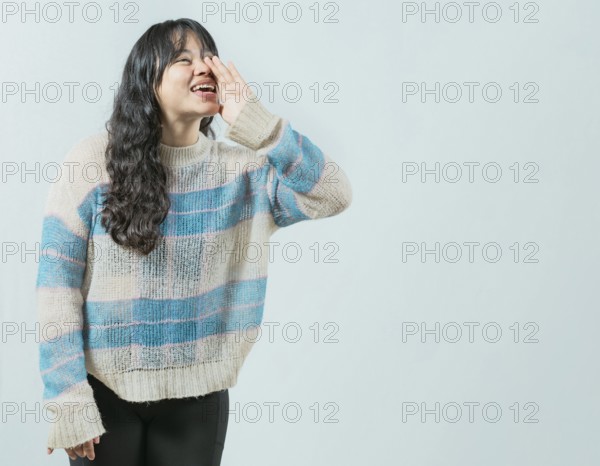 Beautiful asian girl shouting a promotion isolated. Young asian woman shouting an announcement