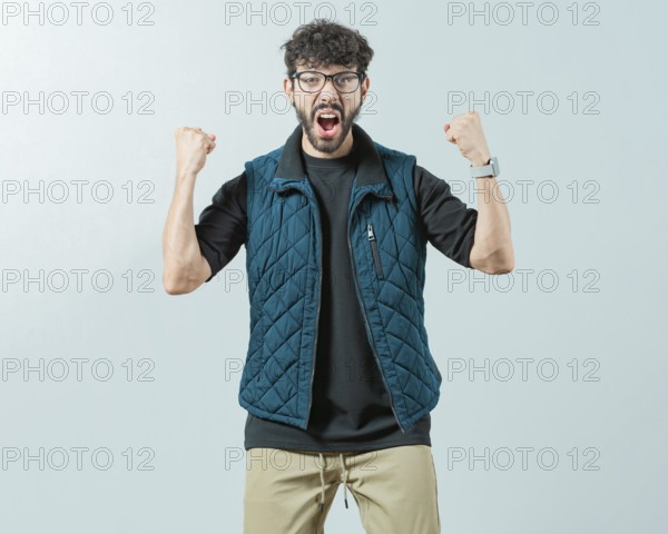 Excited young man celebrating looking at camera raising arms isolated. Happy guy with sunglass celebrating something
