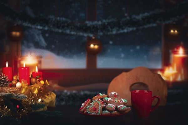 Festively decorated table with candles and cookies in front of a snowy window at night