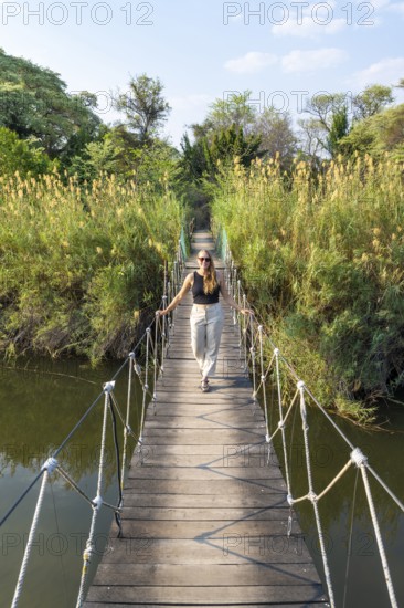 Toruist on the Kavango River, suspension bridge at Camp Kwando, Zambezi region, Caprivi Strip, Namibia