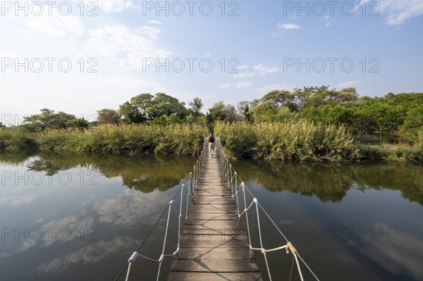 Toruist on the Kavango River, suspension bridge at Camp Kwando, Zambezi region, Caprivi Strip, Namibia