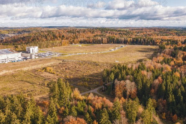 Industrial area and building surrounded by extensive fields and thick forests in autumn, new Lindenrain industrial park, Calw, Black Forest, Germany