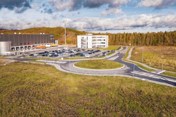 Building complex and roundabout in autumn landscape under blue sky, new Lindenrain industrial park, Calw, Black Forest, Germany